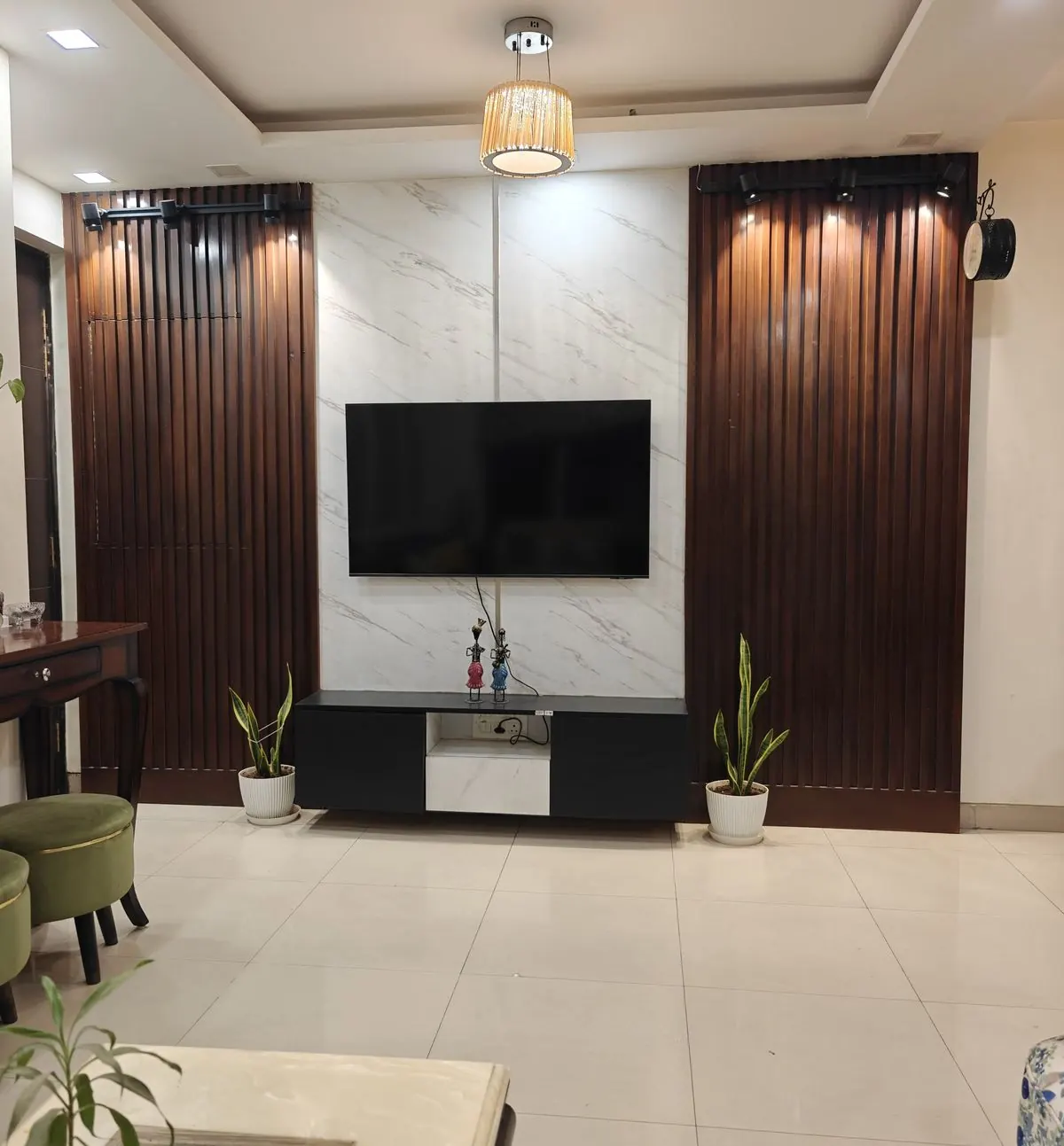 TV wall in white marble between dark fluted wood panels, Gurugram home by Nuvasah Interiors